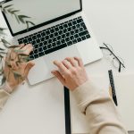 An overhead view of a person working on a laptop in a minimalist home office setting.